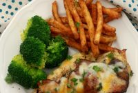 An overhead shot of Alice Springs Chicken on a white plate with broccoli and french fries. It is on a white table with teal pola-dotted and paisley napkins.